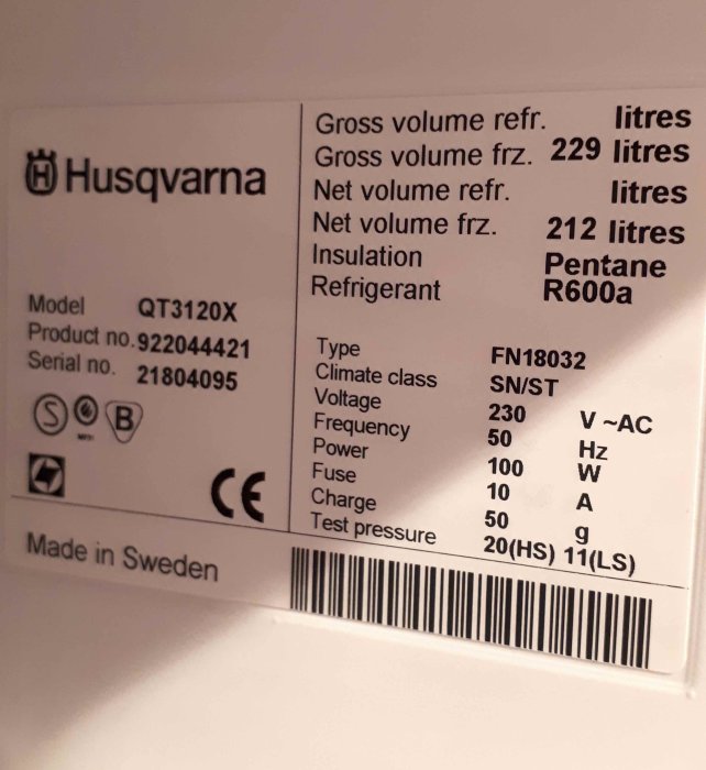 Etikett på Husqvarna frys med modell, produkt- och serienummer samt specifikationer på volym och elektriska data.