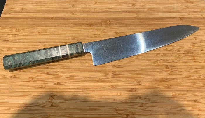 Kockkniv med eget gjort handtag i flerfärgat material på bambu skärbräda.