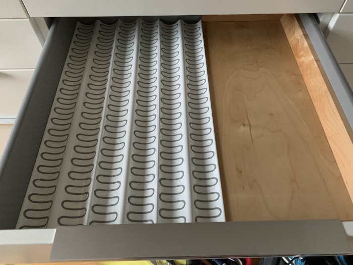 Flagnande kökslucka nära gångjärn, tecken på åldring, behov av underhåll eller utbyte.