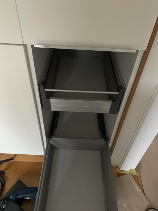 Kökslucka med flagnande färg ovanför öppen låda, synligt gångjärn märkt "blum".
