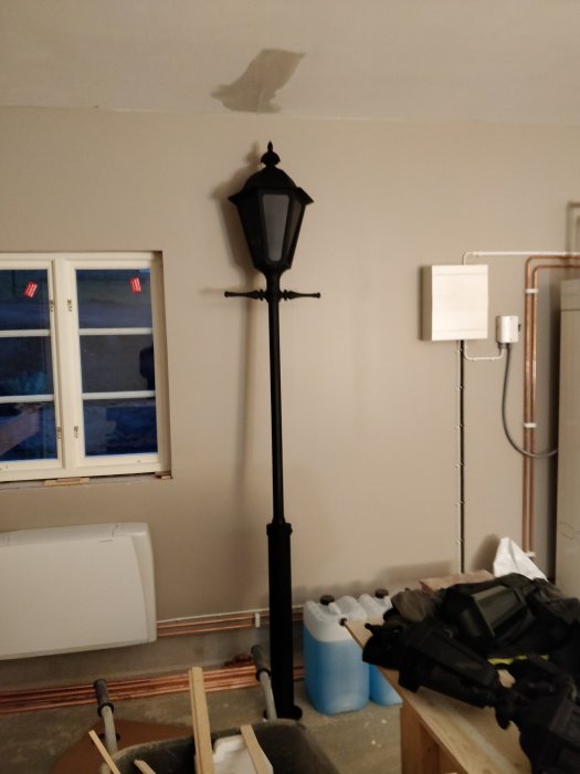 Golvstående utomhuslampa inomhus under installation, verktyg och byggmaterial synliga i ett pågående renoveringsprojekt.