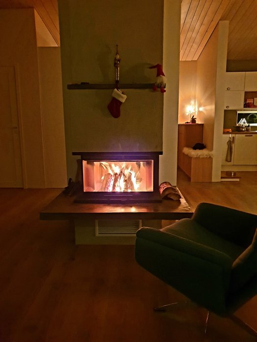 Mysigt vardagsrum med brinnande öppen spis, julstrumpa och tomtenisse på hyllan.