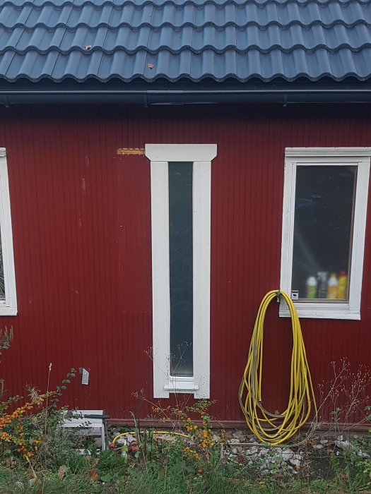 Nyinstallerad ribbad konstruktionsplywood under husfönster på röd vägg, nästan färdigt projekt.