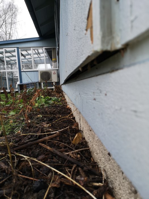 Delvis avtagen ytterpanelskiva på husvägg som visar en fuktig bakomliggande skiva och luftspalt.