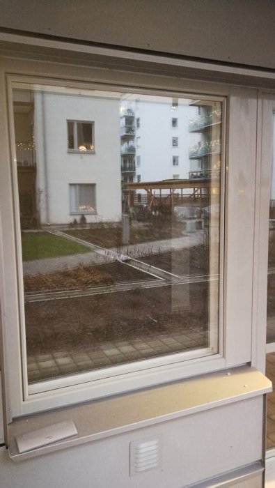 Fönster med nyfogad tegelkant och utsikt över bostadsområde.