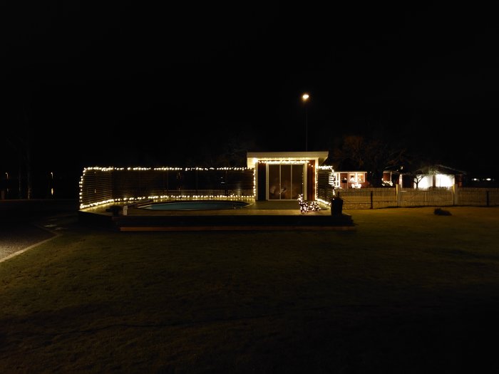 Hus och staket utsmyckade med julbelysning på kvällen innan julafton.