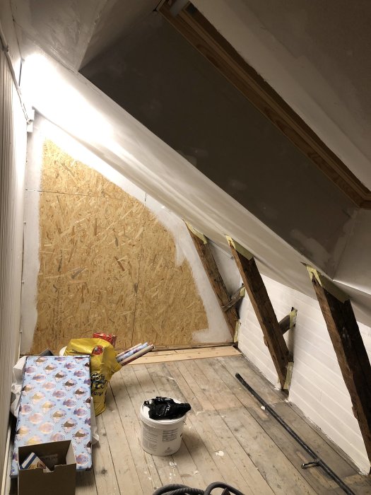 Renovering av garderob med oslipade golvplankor, OSB-skivor på vägg och takspackel.