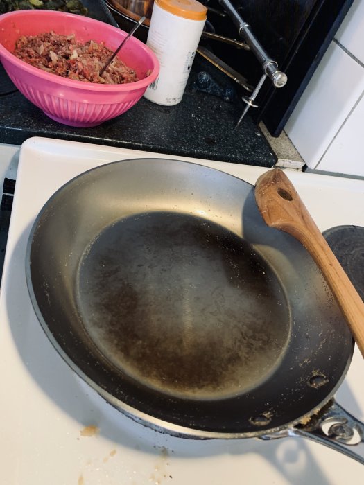 Ny de Buyer stålpanna inbränd med rapsolja på spisen bredvid en skål med älgfärs.