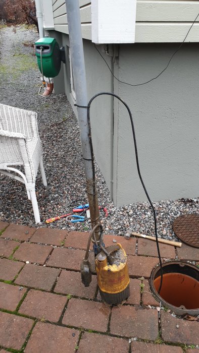 Gamla AL-KO Drain 6001 pumpen som ligger på marksten bredvid öppen brunn.