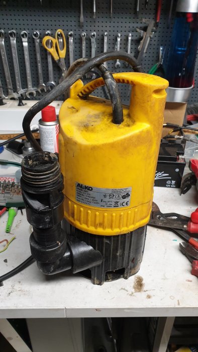 Gul och svart AL-KO Drain 6001 dränkbar pump med skadad kontakt på verkstadsbänk.