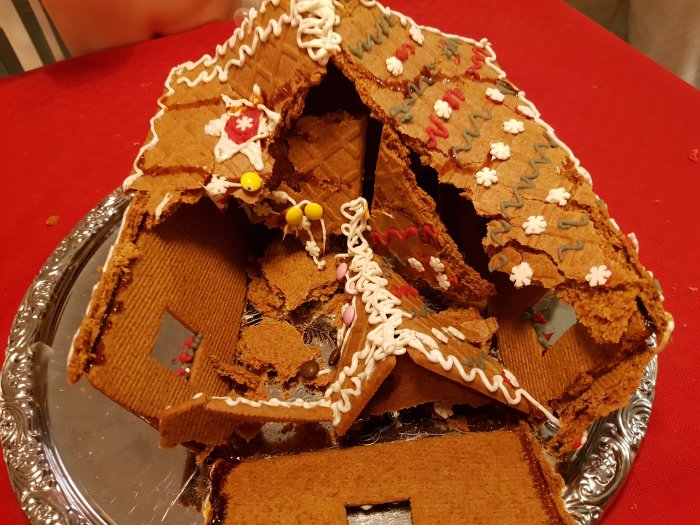 Kollapsad pepparkakshusruin med dekorationer på ett fat, symboliserar en riven byggnad.