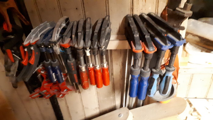Flera olika tvingar upphängda på en organiserad verktygstavla.
