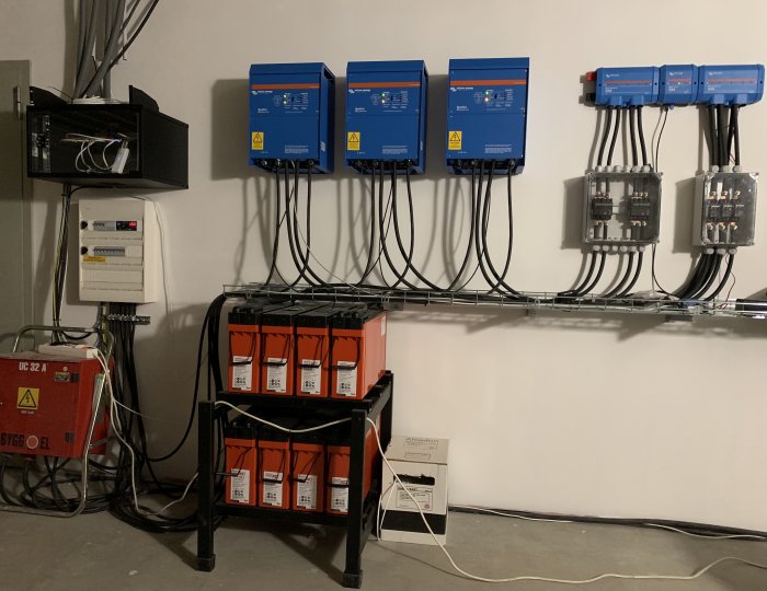 Installation av solenergisystem med växelriktare, strömbrytare, säkerhetsutrustning och batteribank i teknikrum.