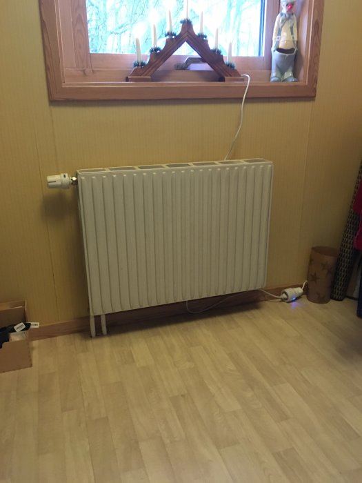 Vattenburen radiator som sticker ut från väggen i ett rum före köksrenovering.