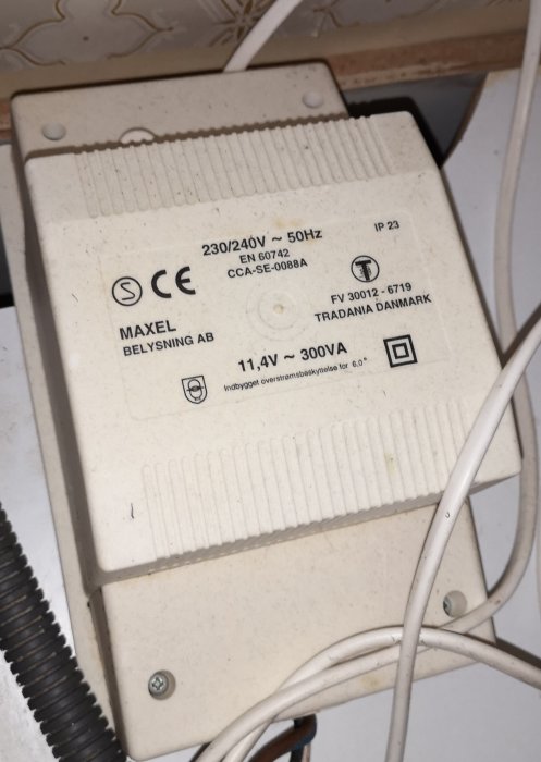 En gammal, dammig dimmer för halogenspottar märkt med "MAXEL BELYSNING AB" och specifikationer "230/240V - 50Hz, 11,4V - 300VA".