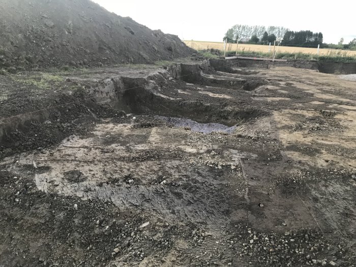 Grundarbeten för ridhus med avtagna matjordslager och förberedda plinthål fyllda med makadam och grus.