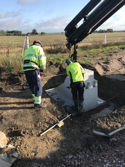 Arbetare placerar en betongplint med hjälp av en kranbil på en byggarbetsplats för ett ridhus.