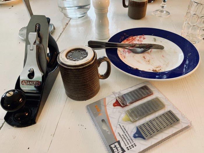 Hyvel och brynen på bordet med använd kaffekopp och tom tallrik i bakgrunden.