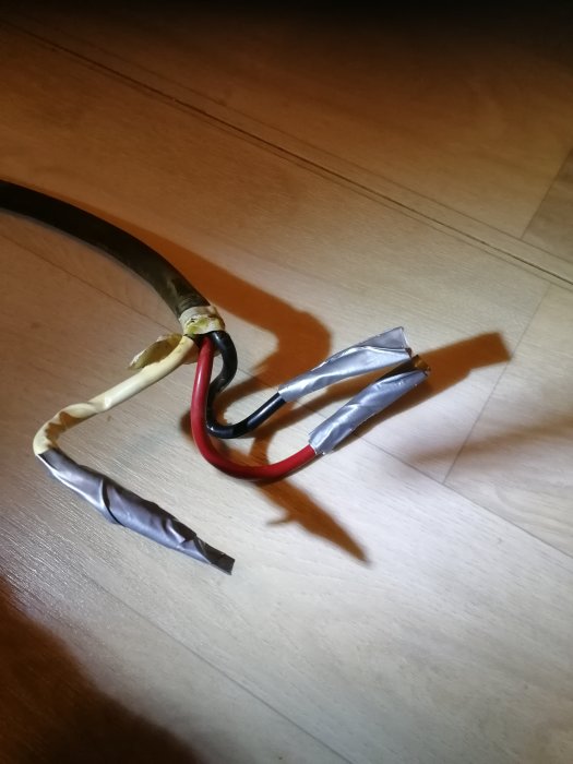 Elektriska ledningar med röd, svart och vit isolering, avskalade och förberedda för anslutning.