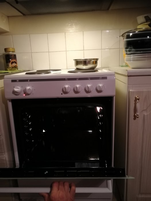 Nyinstallerad vit spis med öppen ugnslucka i ett kök med kakelvägg.