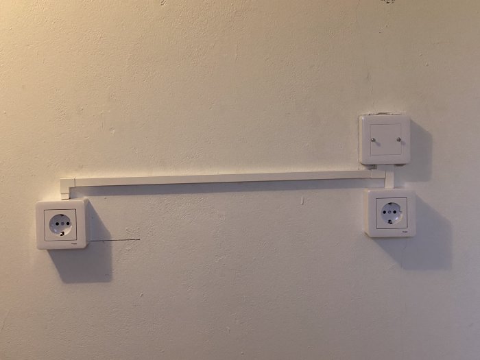 Installerad vit kabelkanal på vägg som ansluter två eluttag med väl märkt ledning i bostadsrenovering.