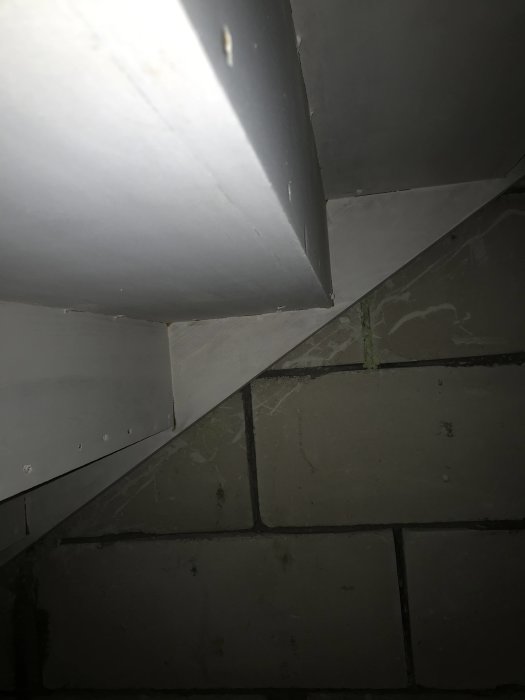 Trappstegsändar mot vit vägg med synliga vagnstycken och en träkonstruktion.