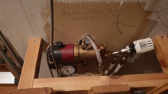 Värmesystem med cirkulationspump, rör och mätare monterade på träpanel.