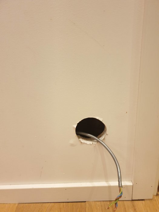 Hål i vägg med utstickande el-kabel, förberedelse för handdukstorkinstallation.