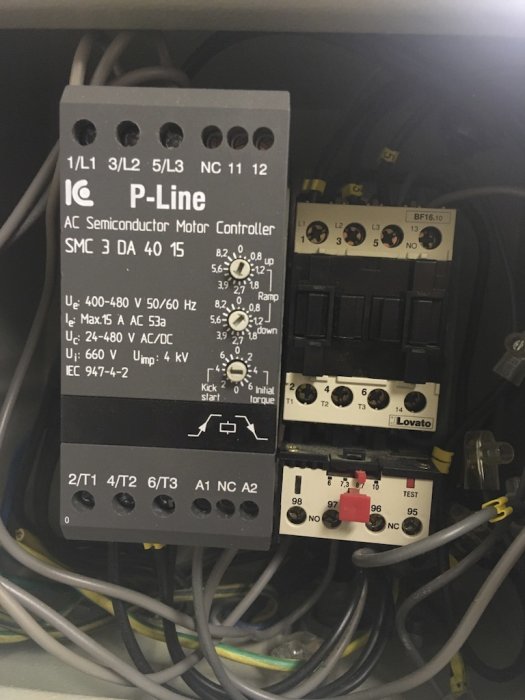 Interiör av elektrisk motorstyrningspanel med märkningar och kabelanslutningar.