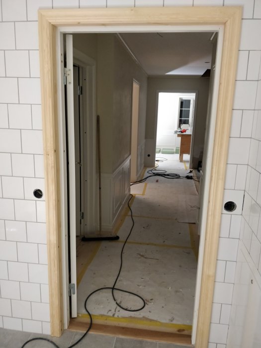 Renoveringsarbete inuti ett hus med oavslutad korridor och kablar på golvet.