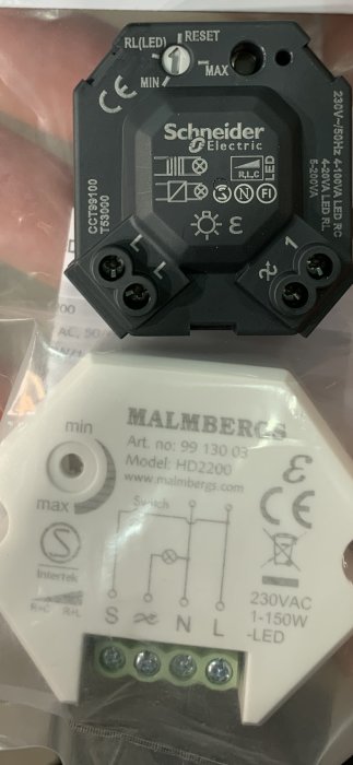 Närbild av en svart Schneider Electric dimmer och en vit Malmbergs dimmer med tekniska specifikationer.