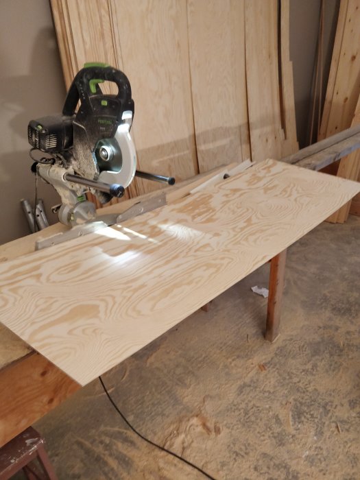 En cirkelsåg kapar ett stycke furuplywood på ett arbetsbänk i ett snickeri.