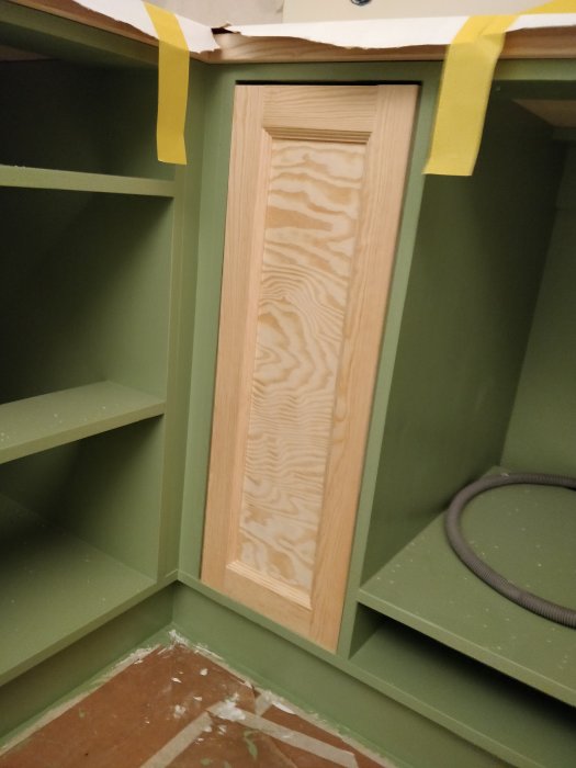 Hemsnickrad kökslucka med ram i planhyvlat trä och spegel i furuplywood, ofärgad och provmonterad i skåpstomme.