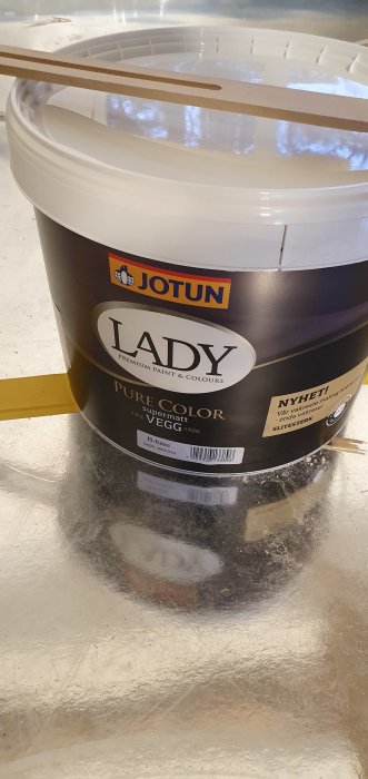 En burk med Jotun LADY Pure Color supermatt väggfärg på ett glansigt underlag.