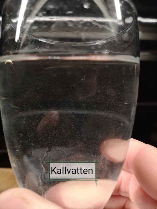 Ett glas med småpartiklar i vattnet och texten "Kallvatten" markerat.