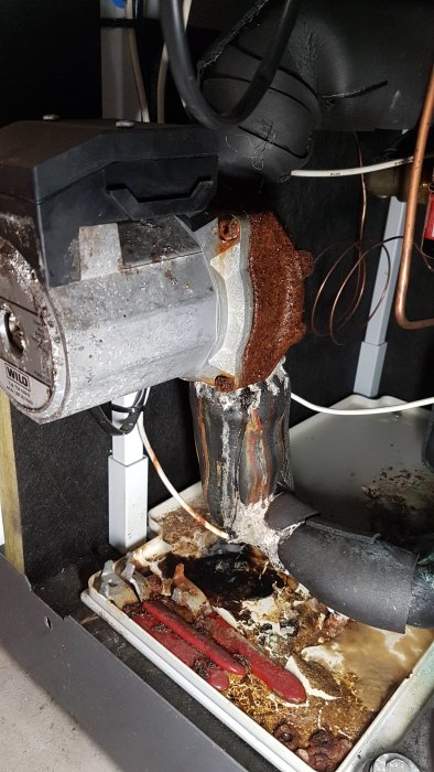 Rost och kondens på cirkulationspump i bergvärmeskåp, med spillplåt nedanför.