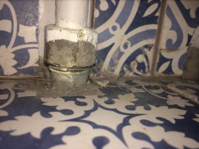 Galvrör med trolig klämringskoppling och vita rördelar vid kaklade väggen.