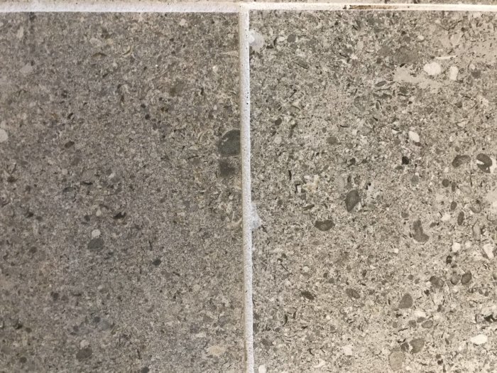 Nahaufnahme eines gefliesten Bodens mit deutlichen Fugen und variierender Textur der Fliesen.