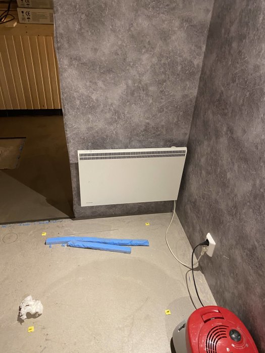 Ojusterat nytt golv med nivåjusteringsklotsar och plattsättning i ett rum under renovering.