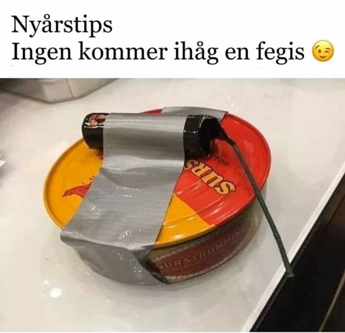 Burk med surströmming tejpfast vid en fyrverkeriraket som förberedelse för uppskjutning.