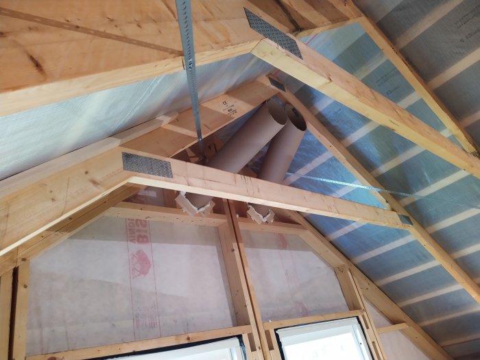 Installation av ventilation i en oisolerad husgavel med dragband och rör som sticker upp över isoleringen.