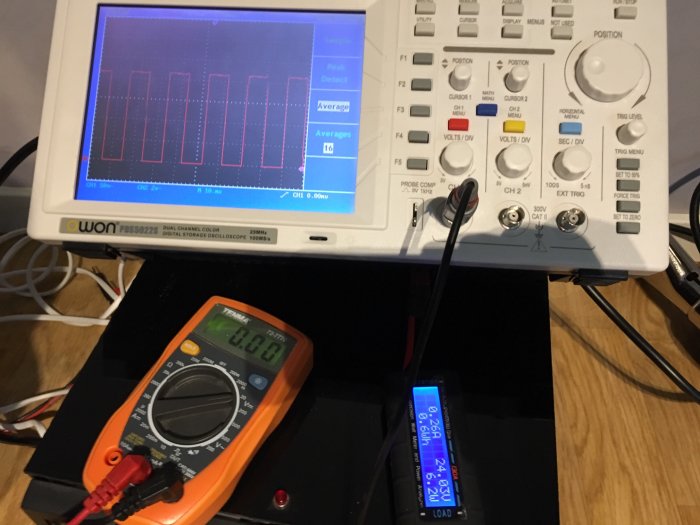 Testutrustning för fläktprojekt med multimeter, oscilloskop och kontrollvoltenhet som visar spänningsdata.