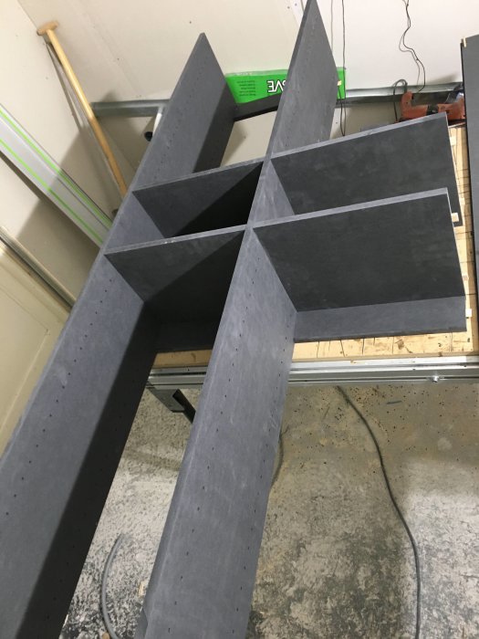 Utsågade trädelar till högskåp med markerade hål före montering i verkstadsmiljö.