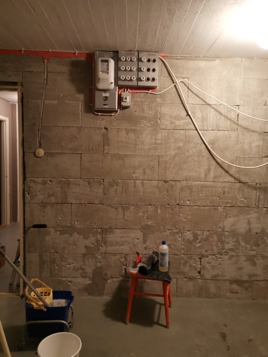 Renoveringsprojekt i källare med ojämnt putsade väggar, en elcentral, och målningsredskap.