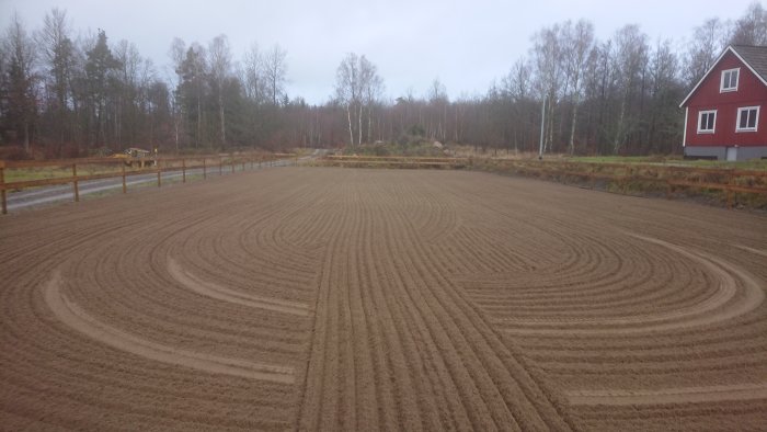 En paddock med nysådda saltspår och ett litet hus i bakgrunden.