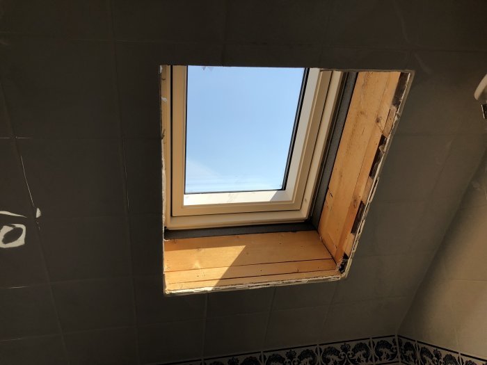 Installation av ett nytt Velux takfönster med solcell och motor, sett inifrån ett badrum där utbytet pågår.