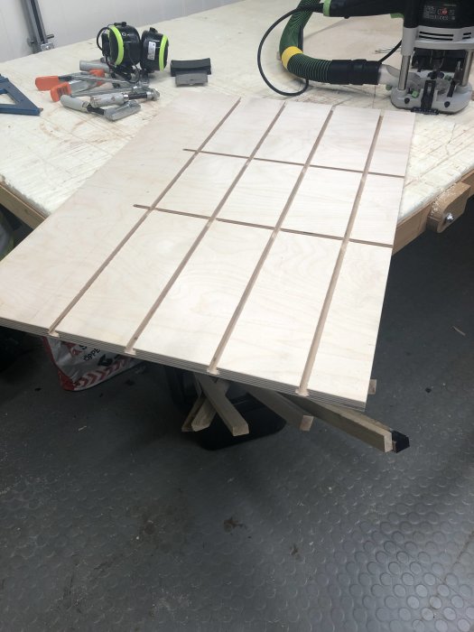 Björkplywood med frästa T-spår i verkstad, förberedd för precision vid byggprojekt.