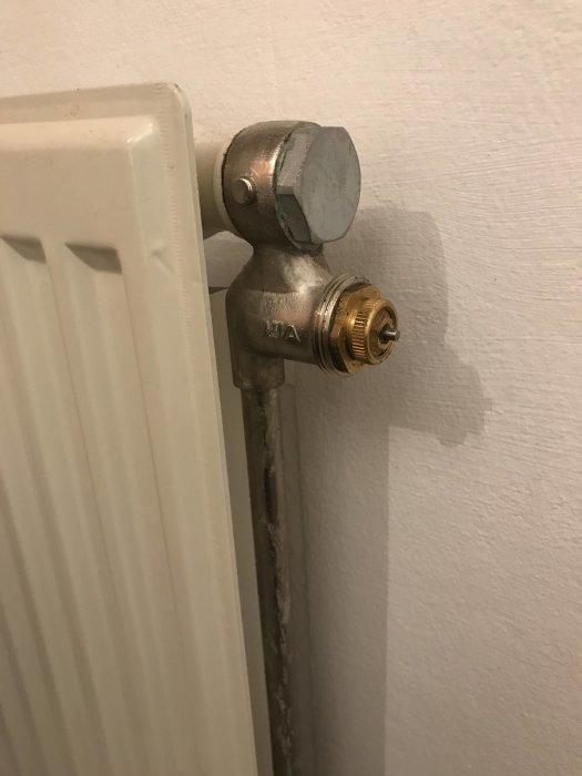 Radiatorventil utan ratt, med synlig gängning där knoppen ska sitta, installerad på vit radiator.