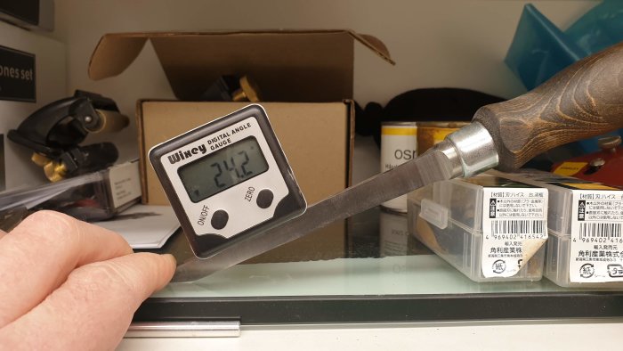 Verktyg mäter vinkel på skärputsad mejsel mot glasskiva med digital vinkelmätare Wixey som visar 24.2°.