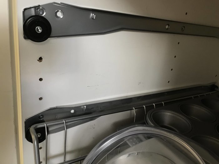Monteringsskena och trådbackar från Metod-systemet installerade i ett vitt skåp.